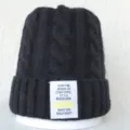 Vue détaillée du bonnet en tricot torsadé noir avec un patch de texte inspirant. - Taille unique / Noir