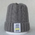 Détail du bonnet en tricot gris avec un patch tissé blanc et une citation inspirante. - Taille unique / Gris