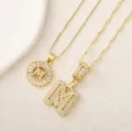 Collar con colgante de letra M de circonita chapado en oro detalle sobre fondo blanco texturizado. - Letra M / Dorado