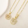 Primer plano detallado de collares con colgante de letra de cristal chapado en oro brillante. - Letra U / Dorado