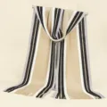 Detailed close-up of the knitted striped scarf texture, fringe details, and color block design. - Beige