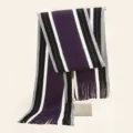 Detailed view of a knitted striped scarf in purple, black, white, and grey with fringe. - Purple