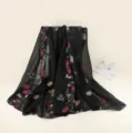 Vue détaillée du châle noir brodé de fleurs colorées montrant des motifs floraux délicats. - Noir