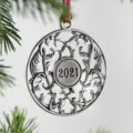 Detailed close-up of a silver metal Christmas tree ornament with 2021 engraved. - 2021