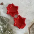 Red plastic snowflake pie mold detail, close-up of festive baking tool with serrated edge. - Star