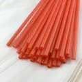 Close-up detail of vibrant orange plastic drinking straws, perfect for DIY crafts or drinks. - Red