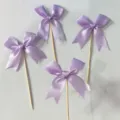 Detailed view of purple satin ribbon bow cake toppers, perfect for dessert party decor. - Purple
