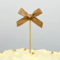 Golden bow cake topper with wooden stick, perfect for birthday party and dessert decoration. - Khaki