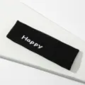 Vista detallada de una diadema deportiva de punto negra con textura de bordado Happy blanca. - Negro HAPPY