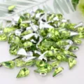 Closeup of teardrop green acrylic rhinestones with silver backing, sparkling crystal details. - Fruit Green