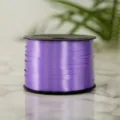 Closeup view of a purple plastic balloon ribbon spool for gift wrapping and party decor. - Deep purple