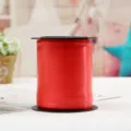 Detalle de rollo de cinta de globo roja, perfecto para decoración de fiesta y envoltorio de regalos. - Rojo Brillante