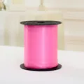 Close-up van een levendige roze ballonlintspoel, perfect voor het inpakken van cadeaus en decoratie. - Roze