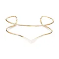 Close-up van de minimalistische metalen armmanchet met een uniek geometrisch kruiswikkelontwerp. - Ossenoorn Stijl (Goud)