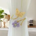 Detailed view of gold butterfly and purple flower curtain tieback, elegant metal decor close up - Purple