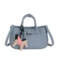 Sac à main bleu clair en cuir grainé avec poignée, bandoulière et pendentif pégase. - Avec Pendentif / Bleu