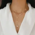 Primo piano di una delicata collana a Y in argento con perle d'acqua dolce su modella - Naturale / Oro Con Perla d'Acqua Dolce Bianca