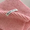 Primo piano di sciarpa in lana lavorata a maglia rosa, scaldacollo invernale morbido. - rosa ciliegia