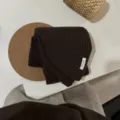 Detailaufnahme eines dunkelbraunen gerippten Strickschals, elegantes und weiches Winteraccessoire. - Kastanienbraun
