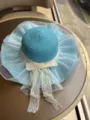 Blauer Strohsonnenhut Detail mit eleganter weißer Schleife und feiner Spitzenverzierung. - Hellblau