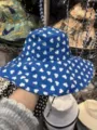 Detailansicht des blauen Eimerhutes mit weißem Herzmuster und verstellbarem Kinnriemen. - Herz Blau