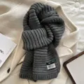 Detailed view of the cozy grey knitted winter scarf texture, soft wool blend fabric. - Gray