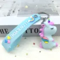 Cute cartoon unicorn keychain with rainbow strap, detailed view of the lovely bag pendant. - Blue Sitting Unicorn