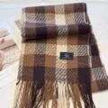 Nahaufnahme eines braunen Karoschals für den Winter mit weicher Fransenoptik und feiner Textur. - Cremiger Kaffee