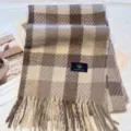 Detail view of a cozy brown and beige plaid winter scarf featuring stylish fringe trim and label. - Milk Khaki
