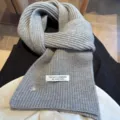 Grey knitted wool blend scarf detail view showcasing handmade label and cute shell button accents. - Gray
