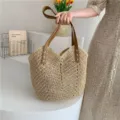 Vista detallada del bolso de mano tejido de paja con asas marrones y textura elegante. - Blanco Roto