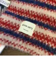 Close-up detail of cozy wool-blend striped knitted winter scarf with brand woven label. - Red and Blue