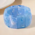 Gros plan d'un bracelet en acrylique bleu avec des motifs marbrés et texturés - Bleu