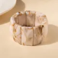 Détail rapproché d'un bracelet en acrylique avec des motifs marbrés marron et crème - Beige