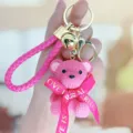 Roze geweven textuur beer sleutelhanger met gouden hardware en bel hanger tas accessoire. - Zittende harsbeer met vlinderdas - Roserood