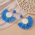 Detail view of blue raffia fan earrings with white beaded centers for holiday style. - Blue