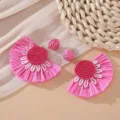 Close-up of pink raffia fan earrings with beaded details and woven prop - Rose Red