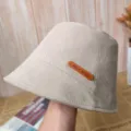 Détail de chapeau bob beige montrant l'étiquette en cuir faite main et le tissu texturé. - Blanc Cassé