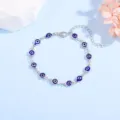 Detailansicht eines silbernen Evil-Eye-Armbands mit blauen Perlen auf blauem Hintergrund - Blauer böser Blick / Silber
