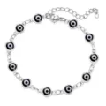 Nahaufnahme eines silbernen Armbands mit schwarz-weißen Evil-Eye-Glücksbringer-Anhängern. - Schwarzes Auge / Silber