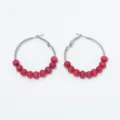 Close-up detail of minimalist retro hoop earrings featuring red wooden beads on metal rings. - Rosewood Beads