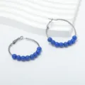Close-up view of blue beaded hoop earrings featuring sleek metal loops on a white textured background - Blue Bead Small Hoop