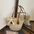 Woven straw beach vacation tote bag for women, stylish hollow design with lace bow and brown handles. - Off White