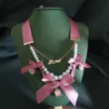 Gedetailleerde close-up van de vintage roze strik parelketting met metalen hanger. - Roze (M230529003-1)