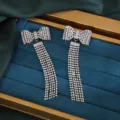 Close-up detail van sprankelende strass strik kwast oorbellen op blauw fluwelen blad. - Zilver
