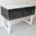 Detailed view of the black fringe curtain table skirt with grid pattern for party decor. - Black
