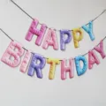 Colorful plush letter birthday banner, macaron style hanging party decoration setup. - Macaron Paper Birthday Banner with Pom-Poms