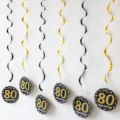 Close-up of black and gold 80th birthday party hanging swirls and card decorations. - 80th Birthday Spiral / Black & Gold