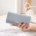 Dettaglio di un portafoglio lungo azzurro con motivo a foglie e chiusura dorata - Blu