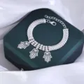 Gedetailleerd overzicht van zilverkleurige hamsa hand armband met strass kettingdetails. - Opengewerkte Hand van Fatima Hanger Stijl (M23030204)